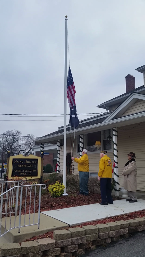 A photo of two elderly man looking up at an American flag