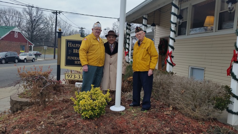 A photo of three gentleman standing beside a flag pole