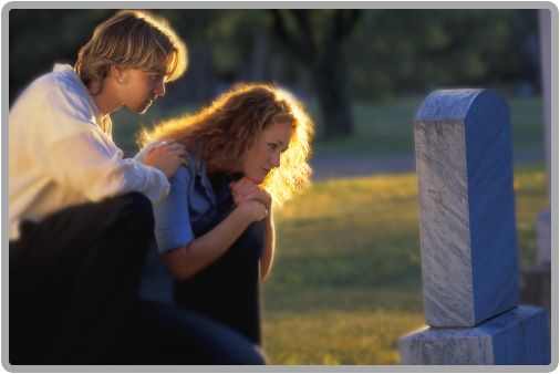 A photo of a man and a woman looking at a grave stone